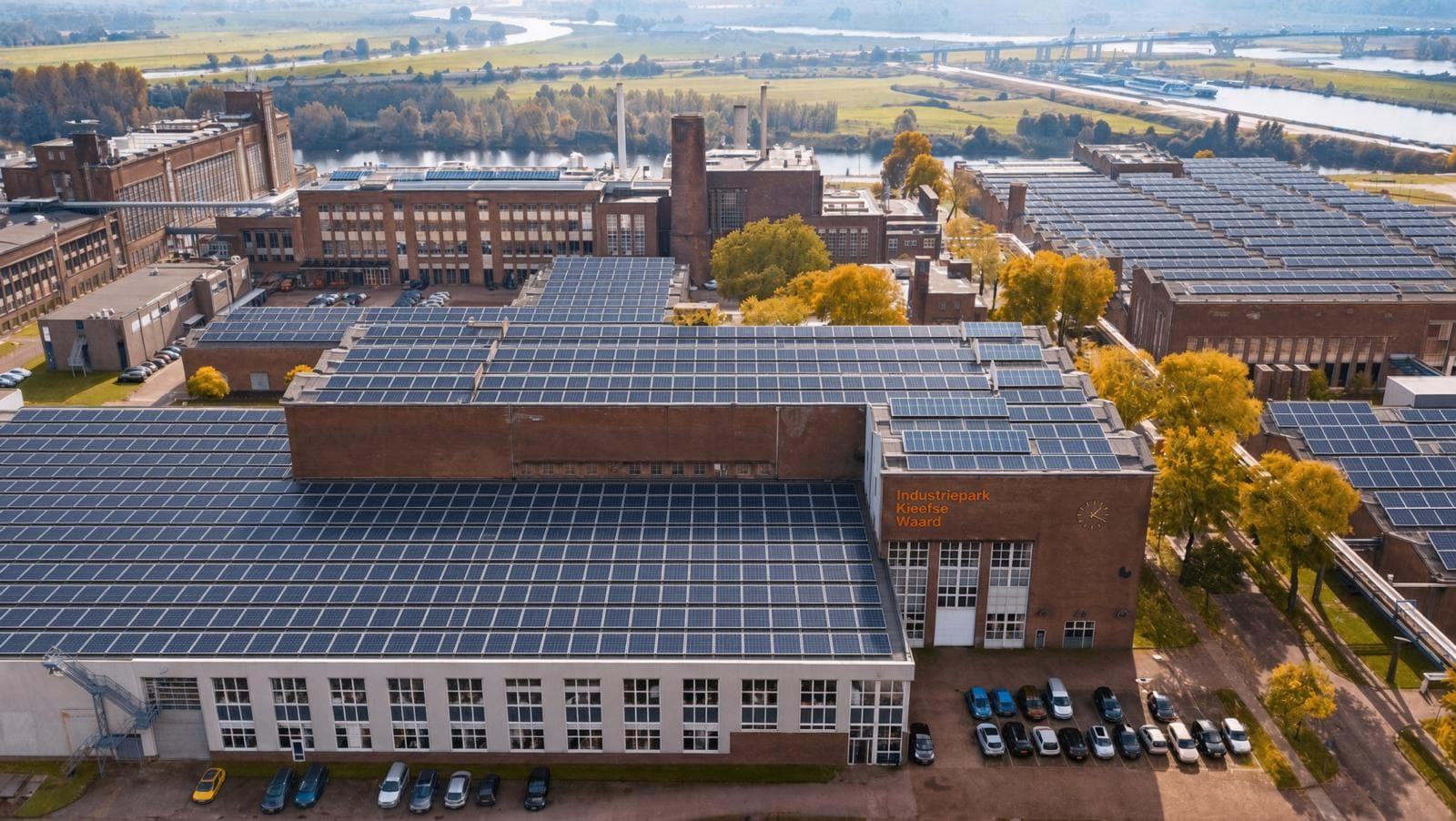 Luchtfoto van een industriepark aan de Nederrijn bij Arnhem, met de hallendaken vol zonnepanelen